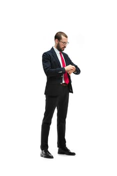 Businessman looking at his watch on his hand, watching the time. portrait of businessman on white studio background. Serious bearded young man in glasses, suit, red tie standing in office. Business concept.