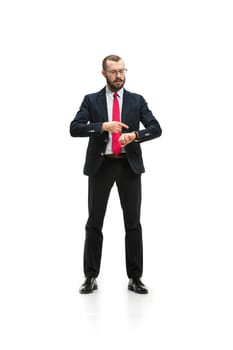 Businessman looking at his watch on his hand, watching the time. portrait of businessman on white studio background. Serious bearded young man in glasses, suit, red tie standing in office. Business concept.