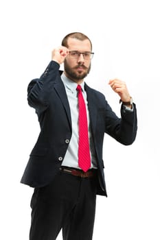 The portrait of businessman on white studio background. Serious bearded young man in glasses, suit, red tie standing in office. Business, career, success concept.