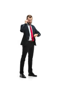 Businessman looking at his watch on his hand, watching the time. portrait of businessman on white studio background. Serious bearded young man in glasses, suit, red tie standing in office. Business concept.