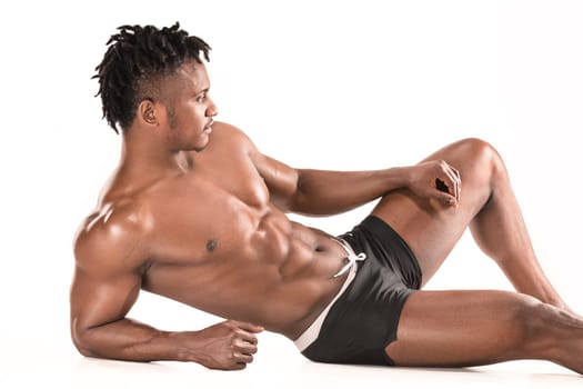 Fit young man with beautiful torso, isolated on white background. The naked torso of African American man posing at studio. The muscular body, fitness, sports, healthy lifestyle and bodybuilder concept.