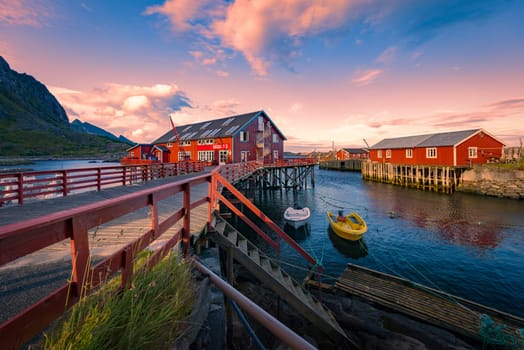 Village of Reine on Lofoten islands in Norway. Traditional red wooden houses and mountains. Sunset sky with clouds. Travel in Scandinavia, Europe.