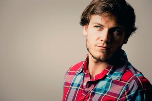 Fashion portrait of a handsome man with trendy hairstyle in a stylish shirt on light green background