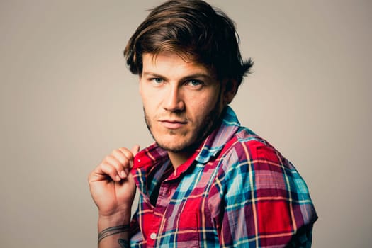 Fashion portrait of a handsome man with trendy hairstyle in a stylish shirt on light green background