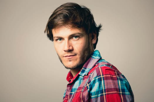 Fashion portrait of a handsome man with trendy hairstyle in a stylish shirt on light green background