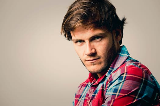 Fashion portrait of a handsome man with trendy hairstyle in a stylish shirt on light green background