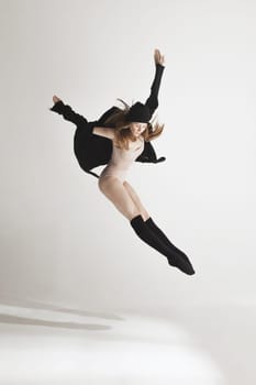 Young beautiful dancer in beige swimsuit dancing on gray studio background. Front view. Young female classical ballet dancer. Ballerina project. Modern choreography, contemporary. Fit caucasian moman