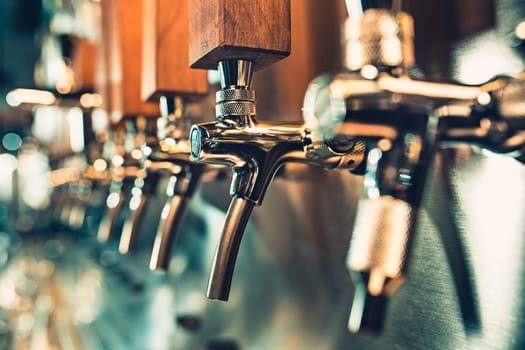 The beer taps in a pub. nobody. Selective focus. Alcohol concept. Vintage style. Beer craft. Bar table. Steel taps. Shiny taps.