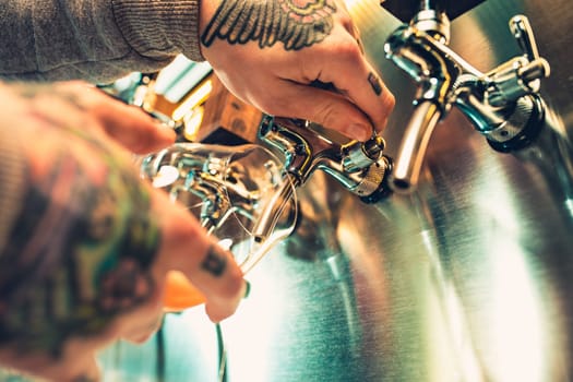 Hand of bartender pouring a large lager beer in tap. Soft, vintage instagram effect on photo. Pouring beer for client. Side view of young bartender pouring beer while standing at the bar counter