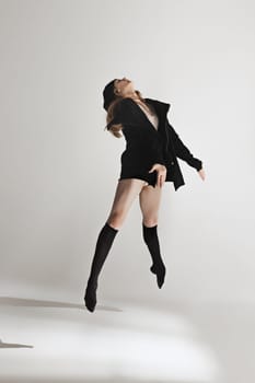 Young beautiful dancer in beige swimsuit dancing on gray studio background. Front view. Young female classical ballet dancer. Ballerina project. Modern choreography, contemporary. Fit caucasian moman