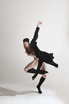 Young beautiful dancer in beige swimsuit dancing on gray studio background. Front view. Young female classical ballet dancer. Ballerina project. Modern choreography, contemporary. Fit caucasian moman