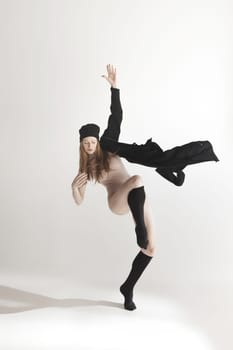Young beautiful dancer in beige swimsuit dancing on gray studio background. Front view. Young female classical ballet dancer. Ballerina project. Modern choreography, contemporary. Fit caucasian moman