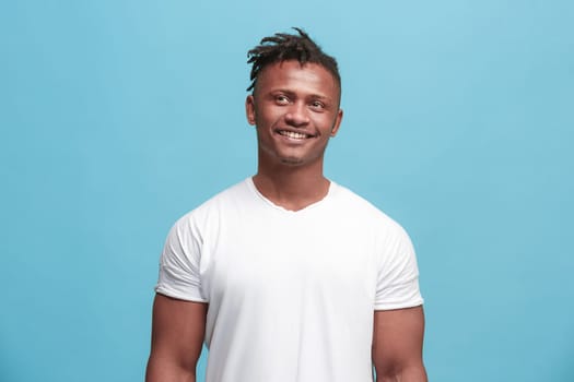 Happy business man standing and smiling isolated on blue studio background. African American male half-length portrait. Young emotional man. The human emotions, facial expression concept. Front view.