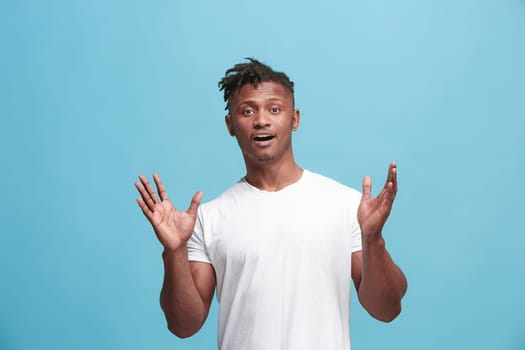 Delight. African american male half-length front portrait isolated on blue studio backgroud. Young, emotional, smiling, surprised man standing. Human emotions, facial expression concept. Trendy colors