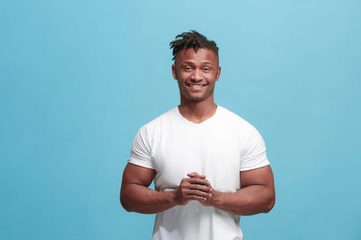 Happy business man standing and smiling isolated on blue studio background. African American male half-length portrait. Young emotional man. The human emotions, facial expression concept. Front view.