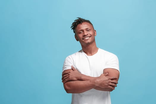 Happy business afro man standing and smiling isolated on blue studio background. Afro-american male half-length portrait. Young emotional man. The human emotions, facial expression concept. Front view.