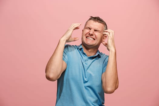 Screaming, hate, rage. Crying emotional angry man screaming on pink studio background. Emotional, young face. male half-length portrait. Human emotions, facial expression concept. Trendy colors