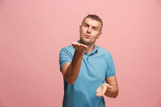 I kiss you. Portrait of attractive man with kiss on lips. Pink studio. Beautiful male portrait. Young happy emotional funny man looking at camera. Human facial emotions concept. Trendy colors