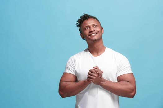 Happy business afro man standing and smiling isolated on blue studio background. Afro-american male half-length portrait. Young emotional man. The human emotions, facial expression concept. Front view.