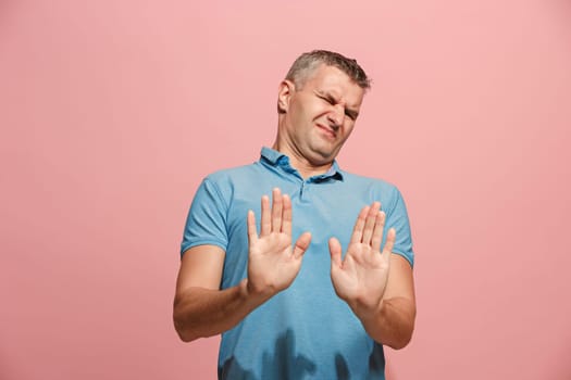 Reject, rejection, doubt concept. Doubtful man with thoughtful expression making choice. Young emotional man. Human emotions, facial expression concept. Front . Studio. Isolated on trendy pink