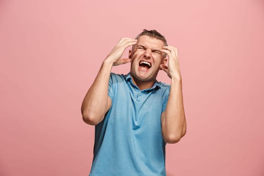 Screaming, hate, rage. Crying emotional angry man screaming on pink studio background. Emotional, young face. male half-length portrait. Human emotions, facial expression concept. Trendy colors