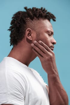 Young man is having toothache. Pain concept. Young emotional man. Human emotions, facial expression concept. Studio. Isolated on trendy blue color. Profile view