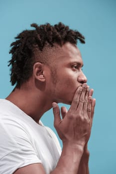 I kiss you. Profile portrait of attractive afro man with air kiss on lips. Blue studio. Beautiful male portrait. Young happy emotional funny man. Human facial emotions concept. Trendy colors