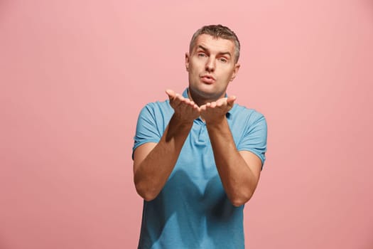 I kiss you. Portrait of attractive man with kiss on lips. Pink studio. Beautiful male portrait. Young happy emotional funny man looking at camera. Human facial emotions concept. Trendy colors
