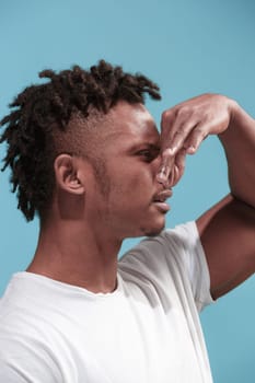 Ew. It's so gross. Young afro man with disgusted expression repulsing something. Disgust concept. Young emotional man. Human emotions, facial expression concept. Studio. Isolated on trendy blue color. Profile view