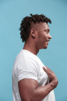 Surprised business Afro-American man standing and looking isolated on blue studio background. African American male profile portrait. Young emotional man. The human emotions, facial expression concept.