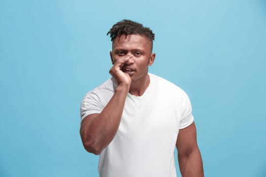 Secret, gossip concept. Young man whispering a secret behind his hand. Businessman isolated on trendy blue studio background. Young emotional man. Human emotions, facial expression concept. afro-american. profile