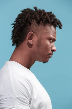 Angry, hate, rage. Emotional angry afro man on blue studio background. Emotional, young face. Profile male half-length portrait. Human emotions, facial expression concept. Trendy colors