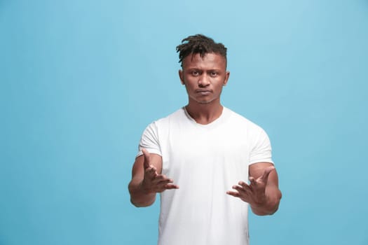 Argue, arguing concept. Beautiful afro male half-length portrait isolated on blue studio backgroud. Young emotional surprised man looking at camera. Human emotions, facial expression concept. Front view
