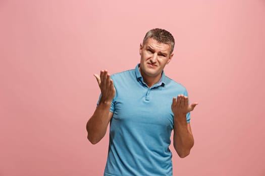 Argue, arguing concept. Beautiful male half-length portrait isolated on pink studio backgroud. Young emotional surprised man looking at camera. Human emotions, facial expression concept. Front view