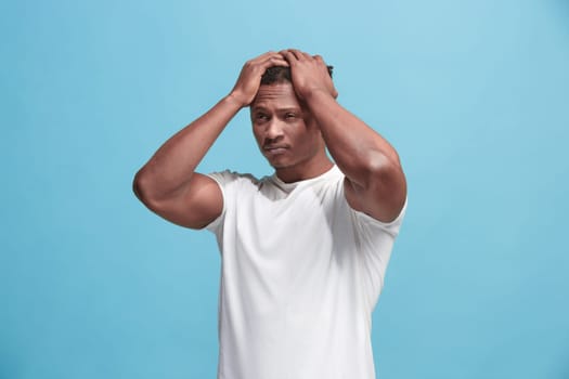 Afro Man having headache. Isolated on blue background. Business man standing with pain isolated on trendy pink studio background. Male half-length portrait. Human emotions, facial expression concept. Front