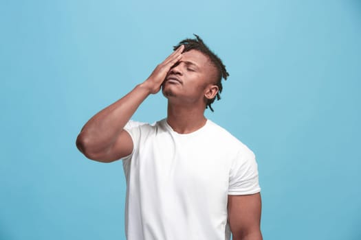 Afro Man having headache. Isolated on blue background. Business man standing with pain isolated on trendy pink studio background. Male half-length portrait. Human emotions, facial expression concept. Front