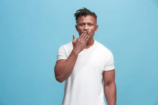 I kiss you. Portrait of attractive afro man with air kiss on lips. Blue studio. Beautiful male portrait. Young happy emotional funny man looking at camera. Human facial emotions concept. Trendy colors