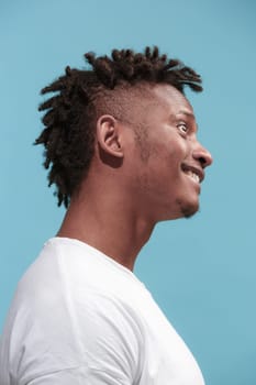 Crazy business Afro-American man standing and wrinkle face isolated on blue studio background. African American male profile portrait. Young emotional man. The human emotions, facial expression concept.
