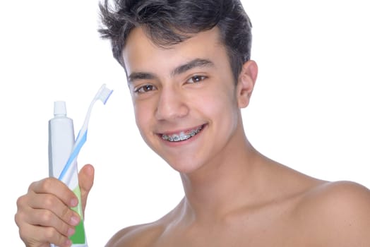 Cute teenager with white background, wearing braces on his teeth. Use toothbrush and toothbrush for cleaning.
