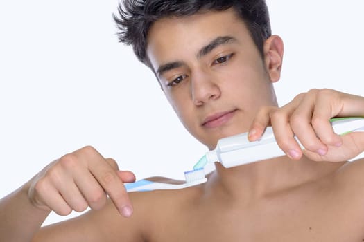 Cute teenager with white background, wearing braces on his teeth. Use toothbrush and toothbrush for cleaning.