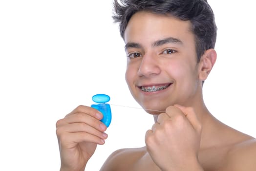 Cute teenager with white background, wearing braces on his teeth. Use dental floss.