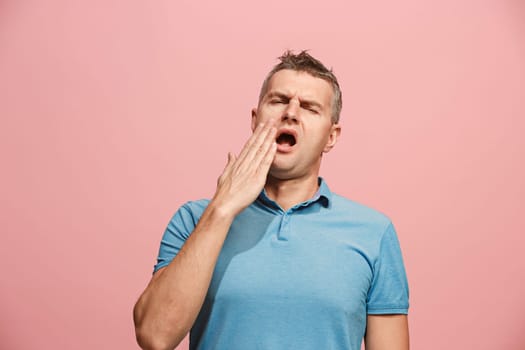 I am tired of everything. Bored man. Boring, dull, tedious concept. Young caucasian emotional man. Human emotions, facial expression concept. Studio Isolated on trendy pink background