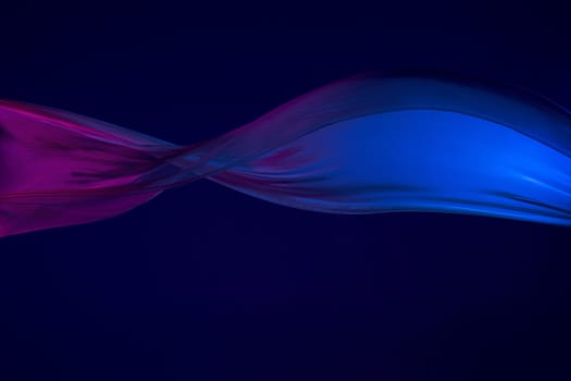 Smooth elegant transparent blue cloth isolated or separated on dark blue studio background. Texture of flying silk fabric.