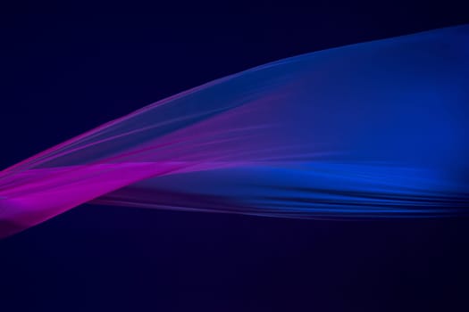 Smooth elegant transparent blue cloth isolated or separated on dark blue studio background. Texture of flying silk fabric.