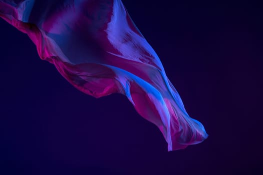 Smooth elegant transparent blue cloth isolated or separated on dark blue studio background. Texture of flying silk fabric.