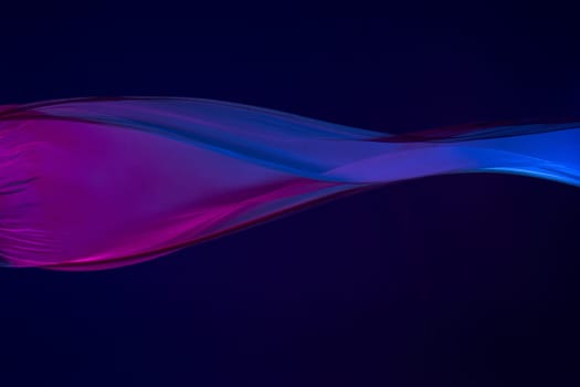 Smooth elegant transparent blue cloth isolated or separated on dark blue studio background. Texture of flying silk fabric.