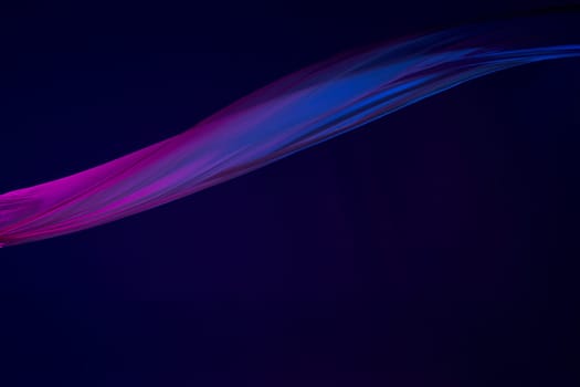 Smooth elegant transparent blue cloth isolated or separated on dark blue studio background. Texture of flying silk fabric.
