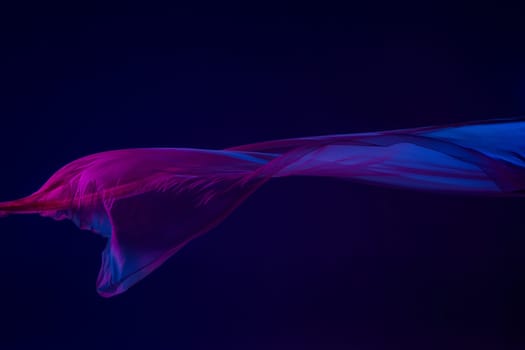 Smooth elegant transparent blue cloth isolated or separated on dark blue studio background. Texture of flying silk fabric.