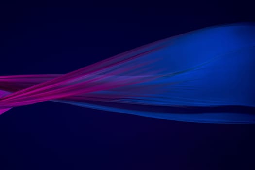 Smooth elegant transparent blue cloth isolated or separated on dark blue studio background. Texture of flying silk fabric.