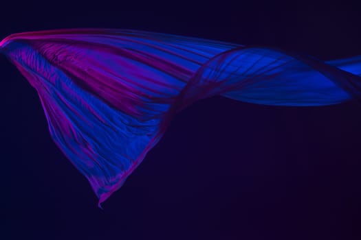 Smooth elegant transparent blue cloth isolated or separated on dark blue studio background. Texture of flying silk fabric.
